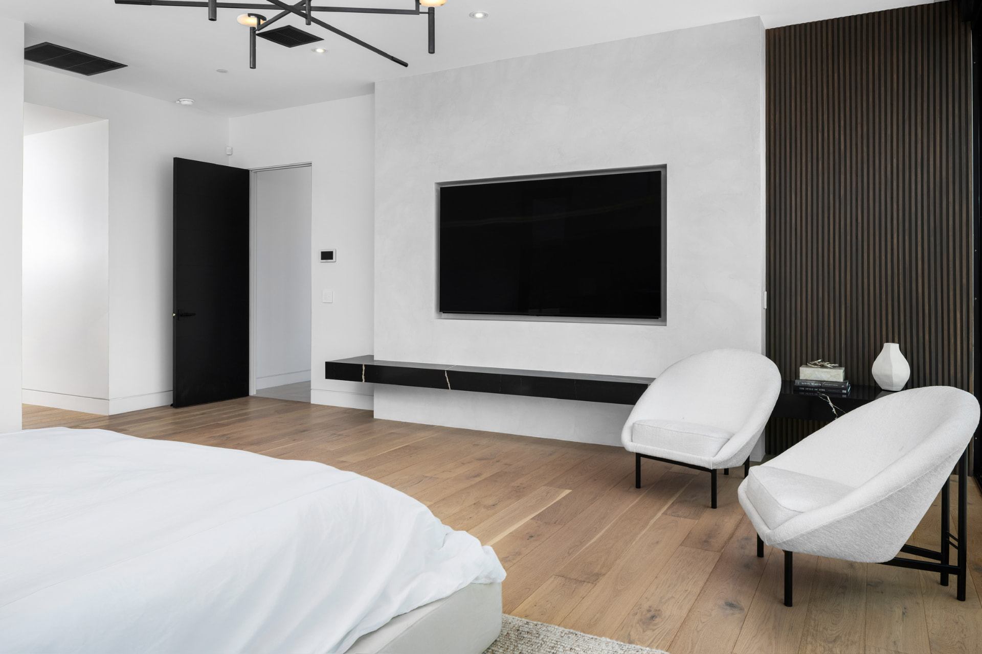 Primary bedroom with lounge chairs and wood feature wall