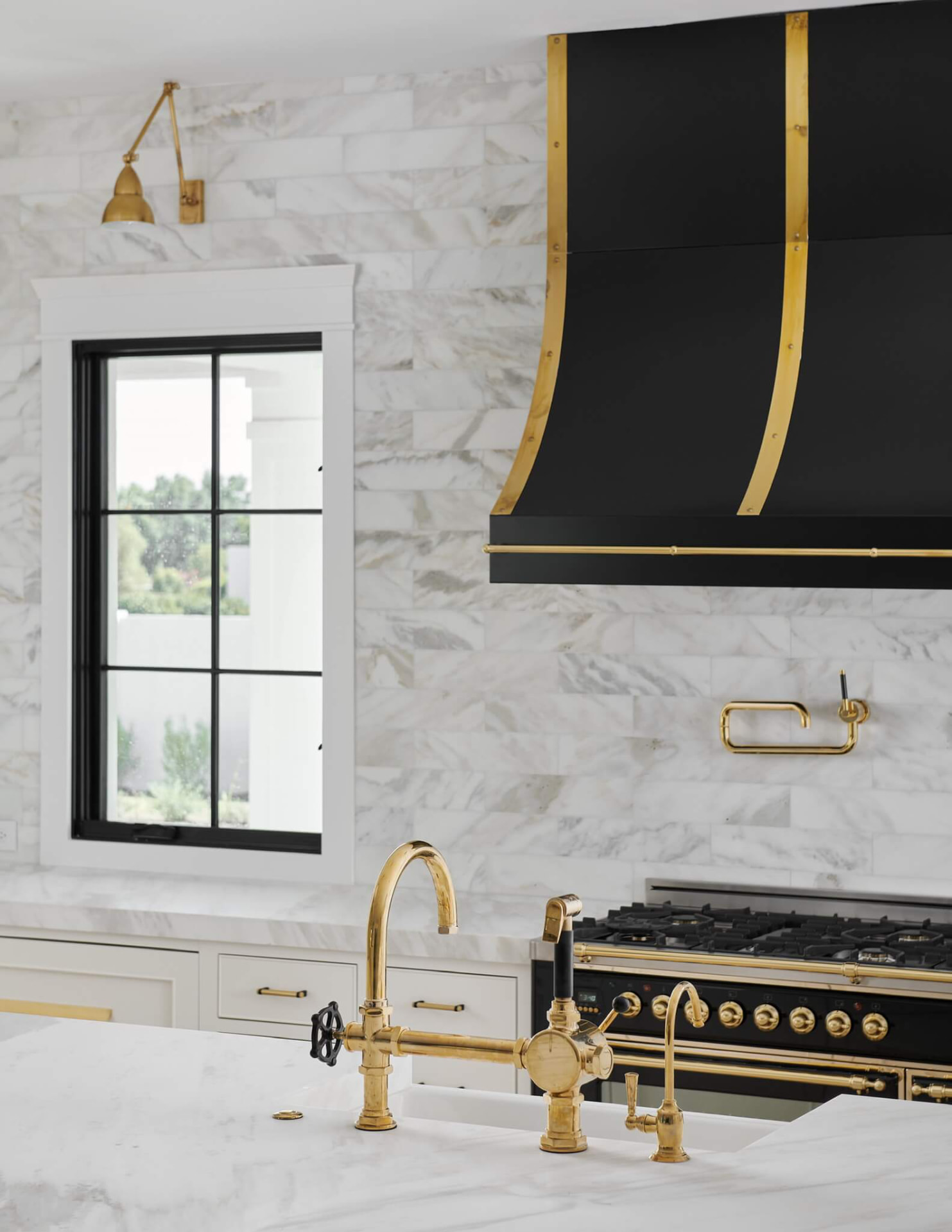 Black and brass range hood against marble