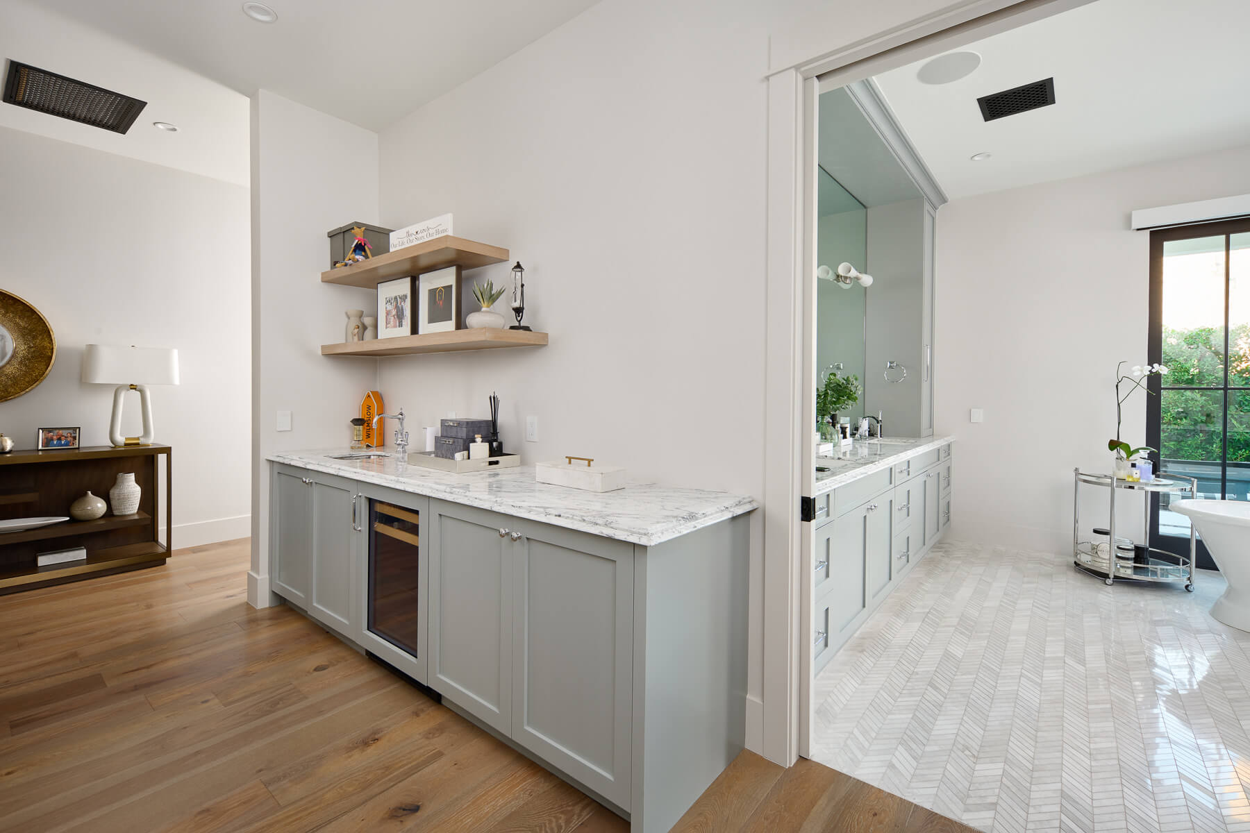 Wet bar with marble counters and gray cabinetry