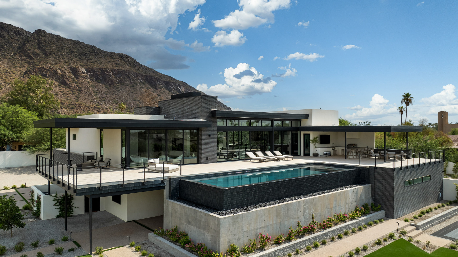 Elevated pool terrace and glass-walled residence in daylight