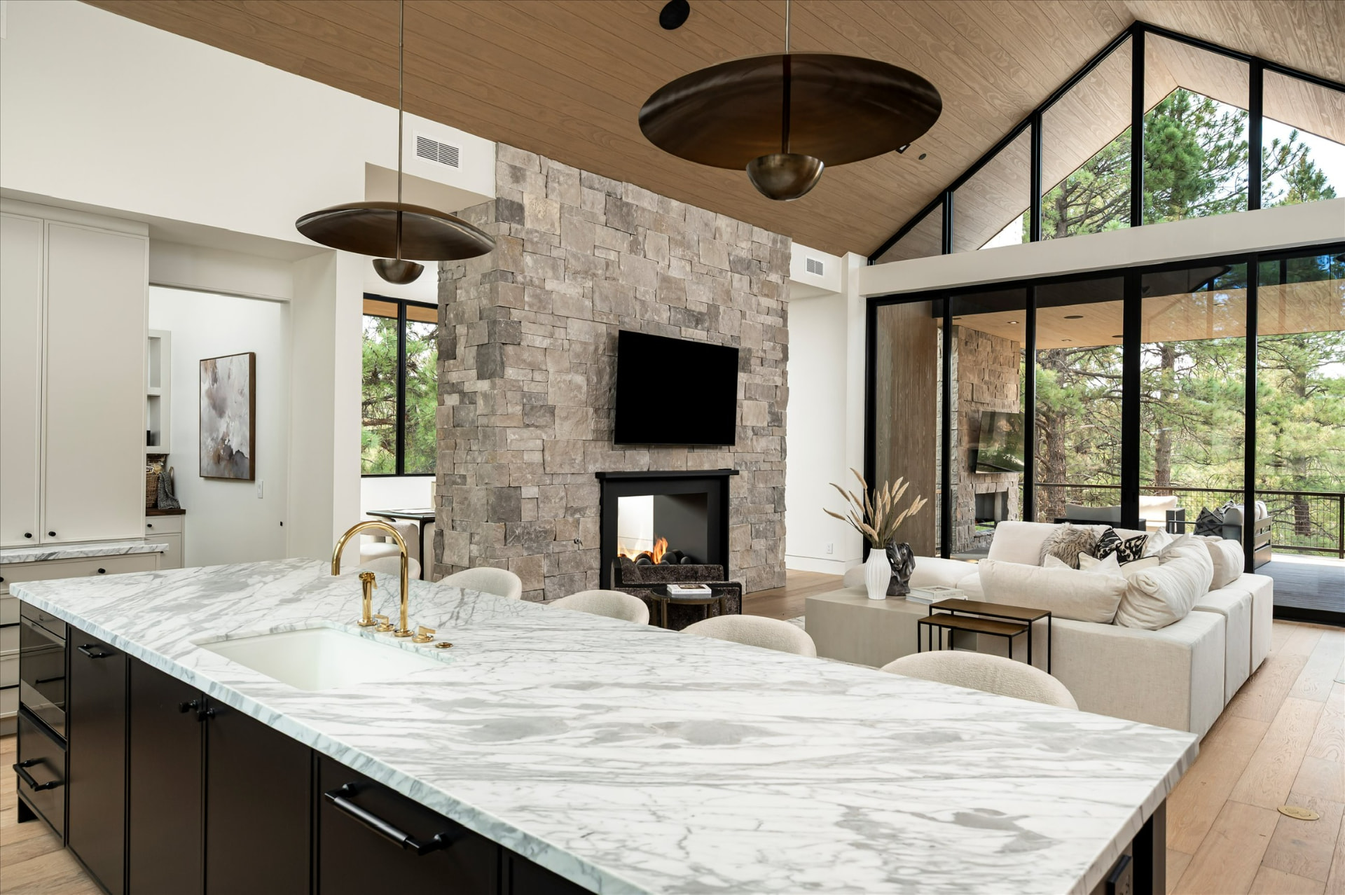 Marble island kitchen with stone fireplace beyond