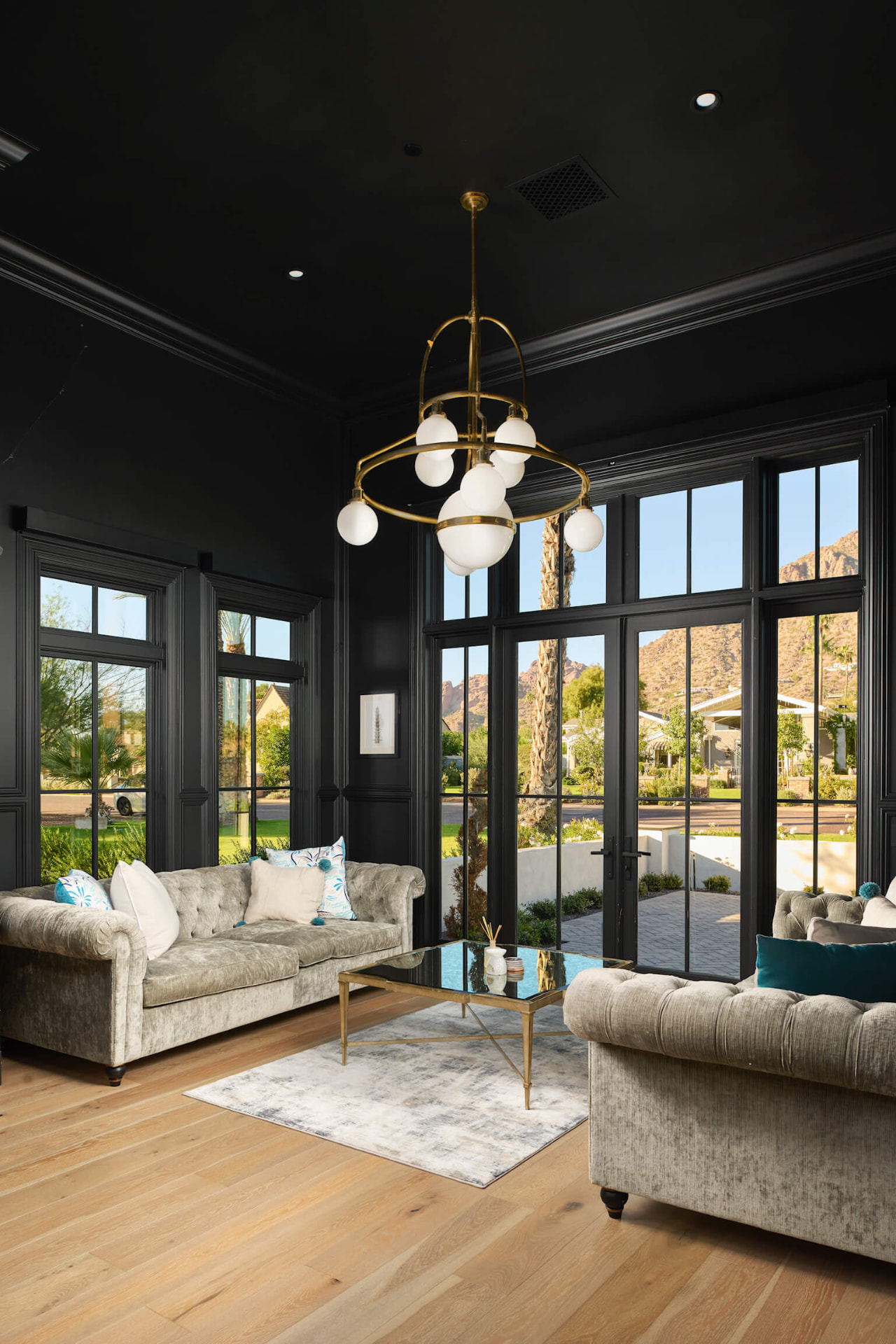 Black-paneled living room with brass chandelier