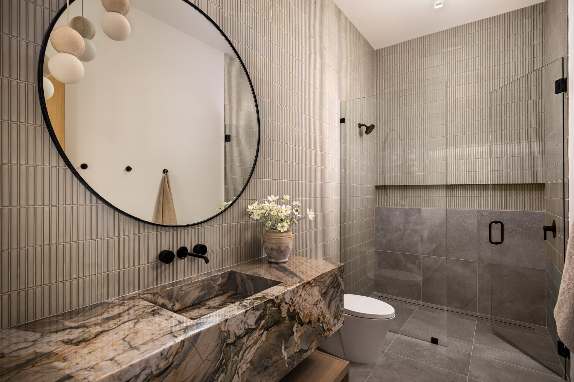 Bathroom with fluted tile, round mirror, and marble vanity