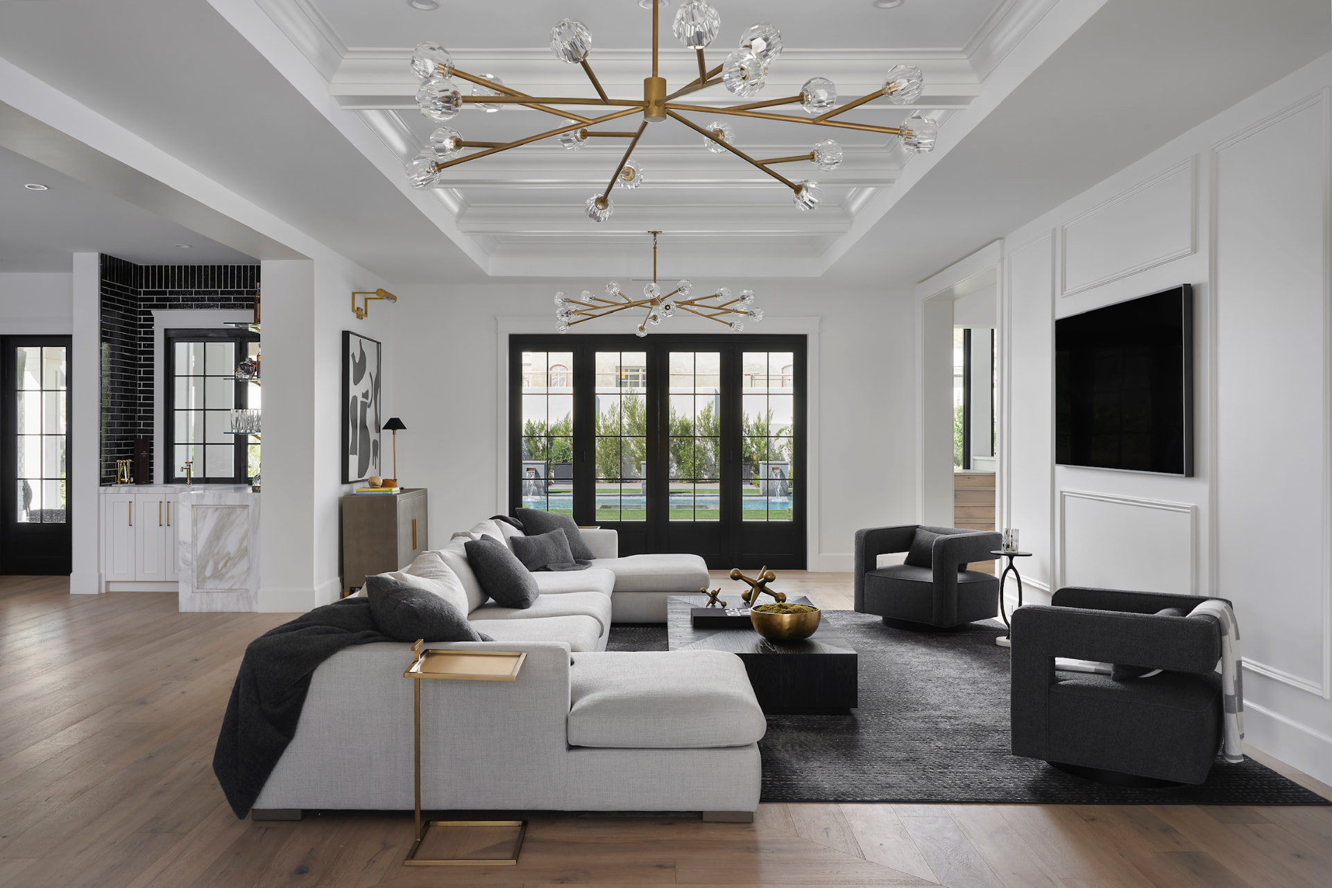 Living room with coffered ceiling and brass chandeliers